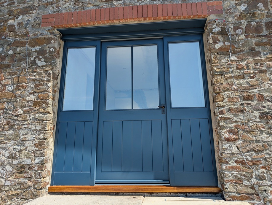Wide timber entrance door screen with balanced glazing, designed and installed for a barn conversion near Rackenford, Mid Devon.