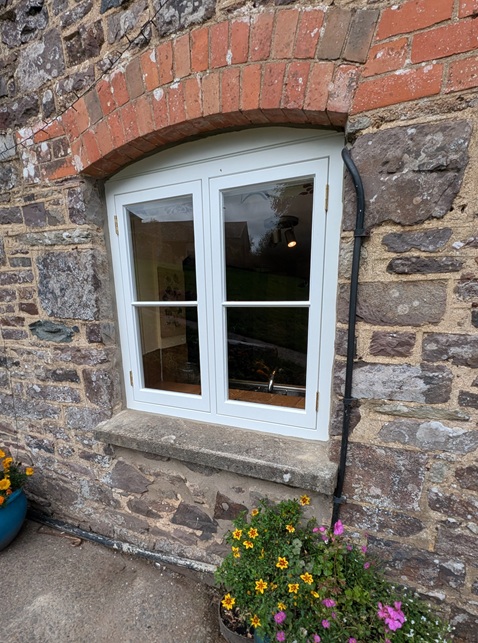 New hardwood flush casement window being fitted into a stone wall