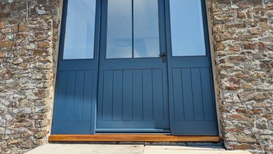 Wide timber entrance door screen with balanced glazing, designed and installed for a barn conversion near Rackenford, Mid Devon.