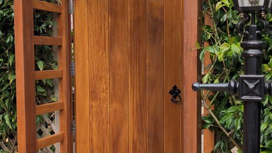 Arched Iroko garden gate shown open within the bespoke timber frame