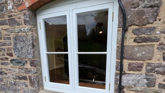 New hardwood flush casement window being fitted into a stone wall