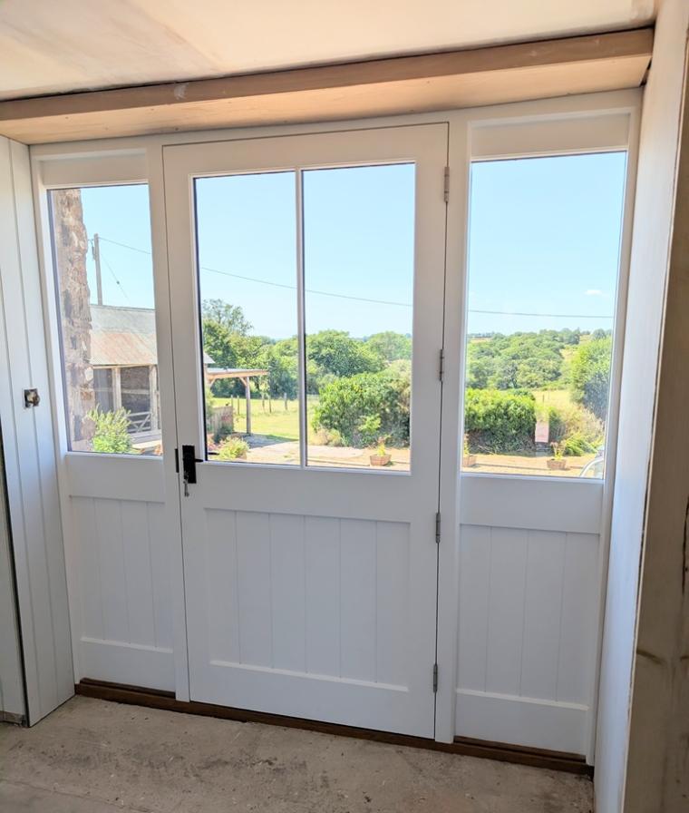 Bespoke wide timber entrance door with clear double glazing, durable stainless steel hinges and a professional Teknos spray finish.