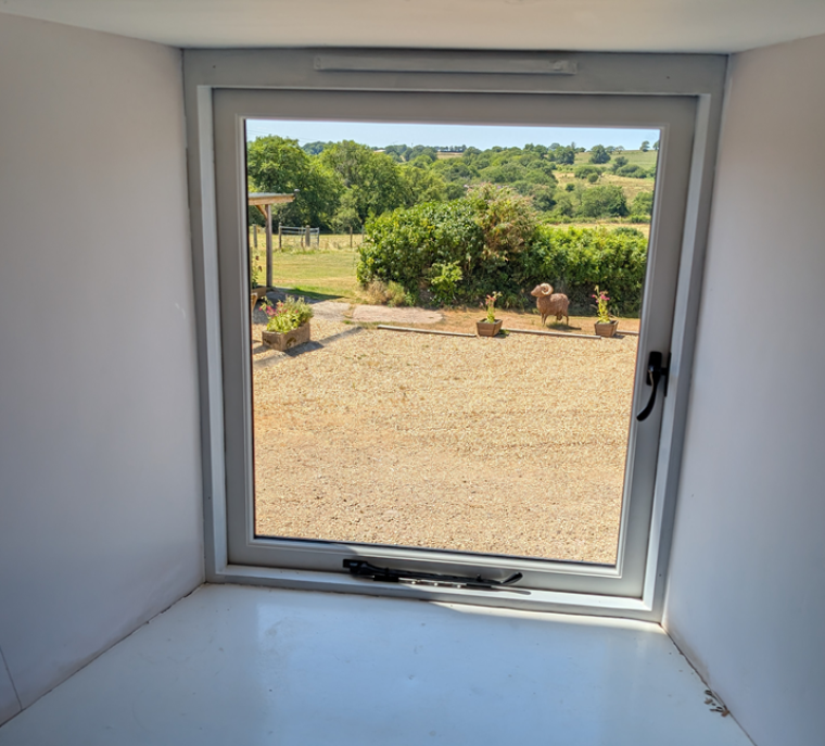 White painted timber window interior helping create a brighter, lighter feel inside the barn conversion while framing countryside views.