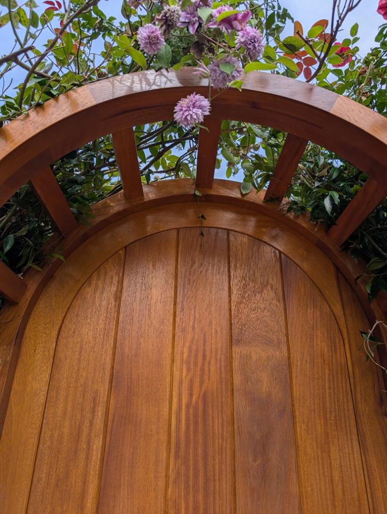 Curved Iroko head forming the top of the garden arbour