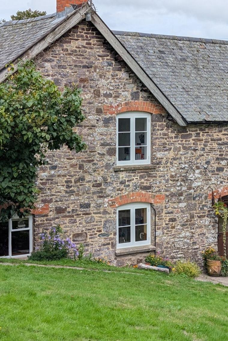 Two new painted timber casement windows in an older stone house in Devon